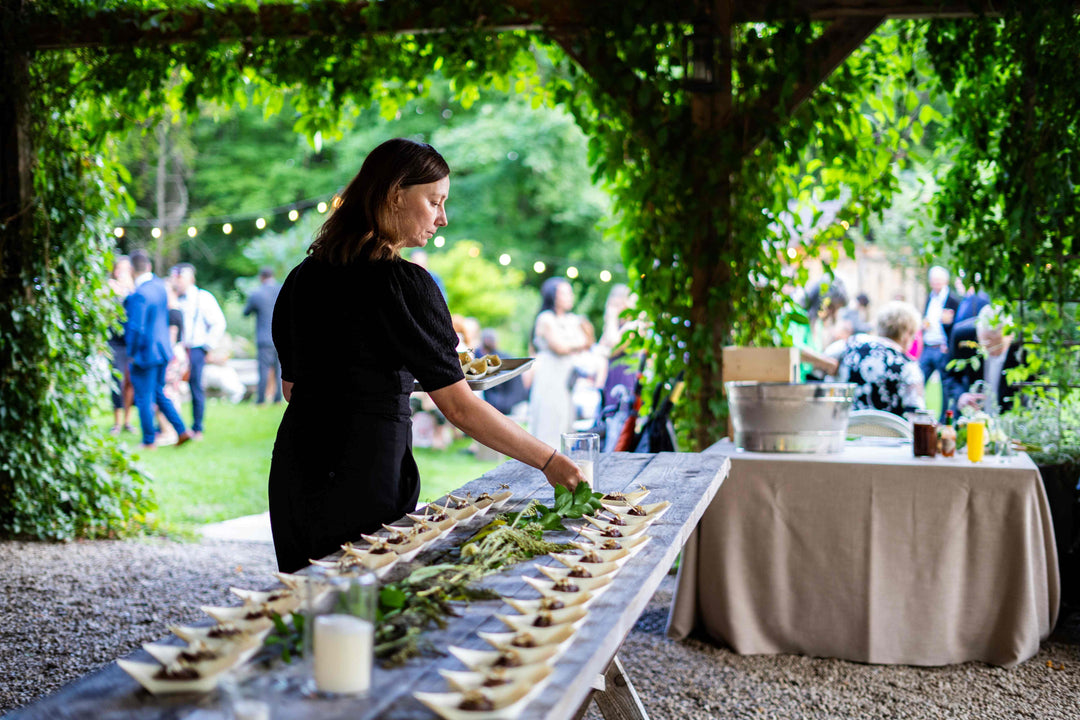 an urban element catering service manager, carefully setting the hot canapes on a table in perfect alignment.