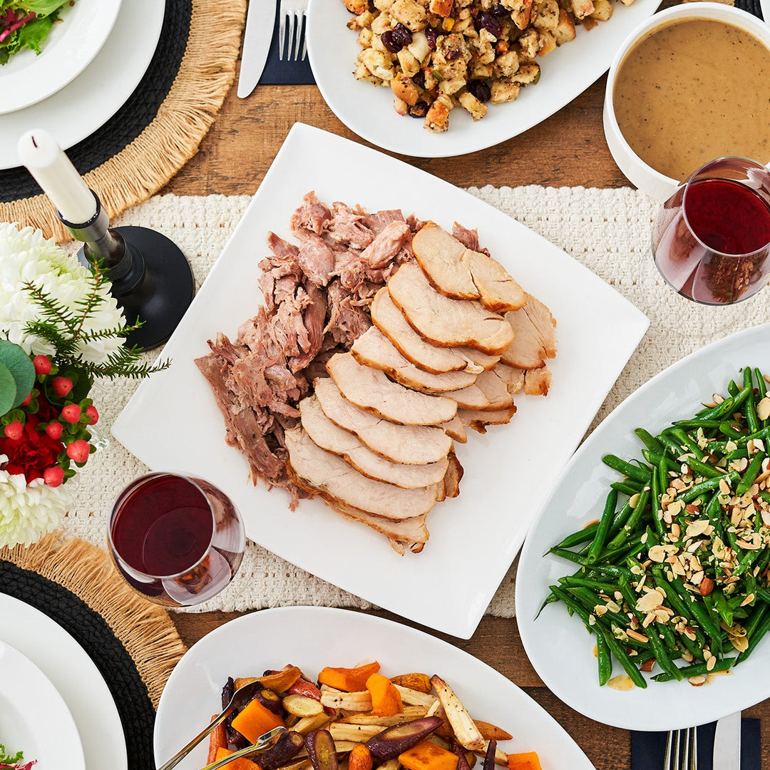 Dinner table set with various dishes including roasted turkey, green beans, and vegetables.