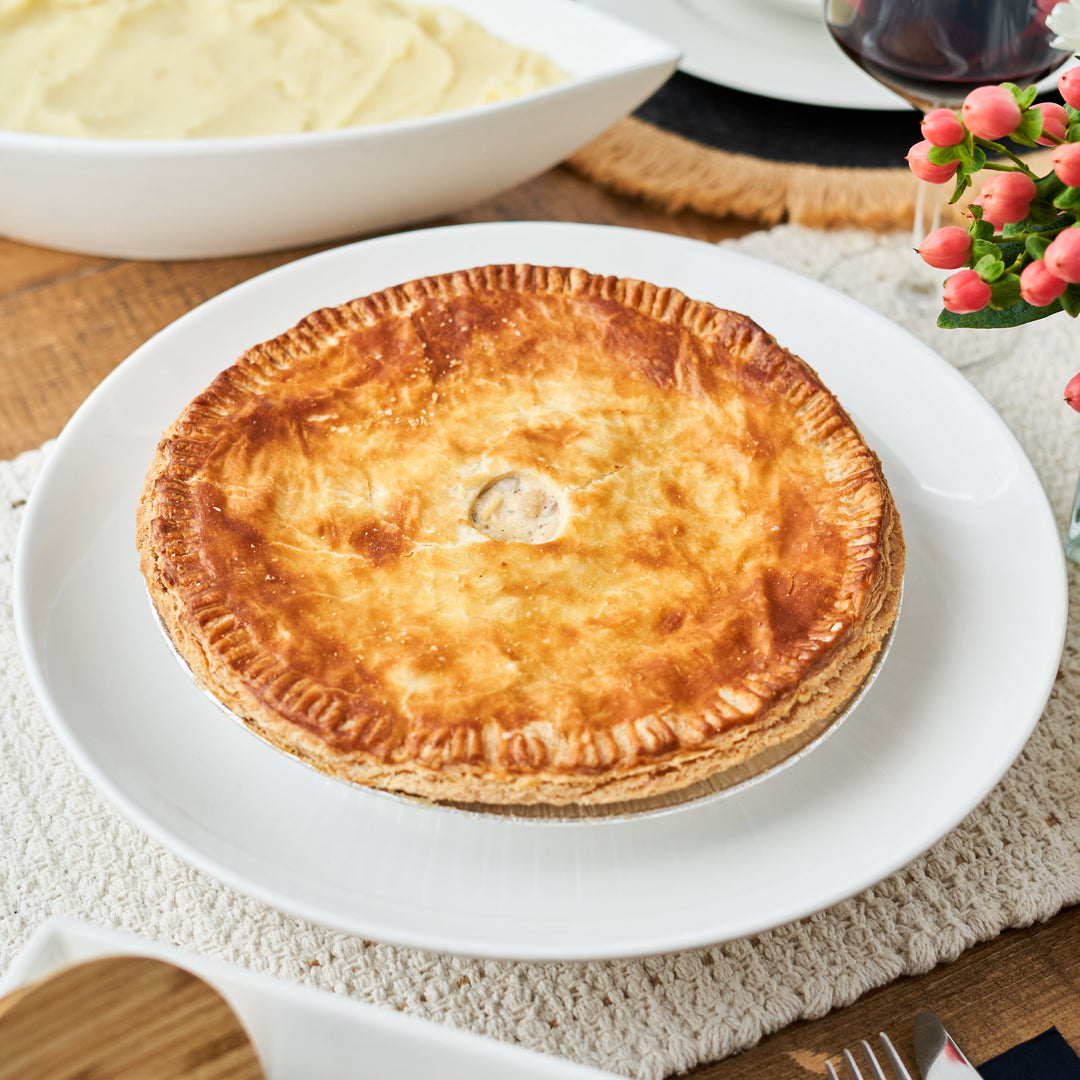 roasted mushroom & white bean pie on a white plate with a side of mashed potatoes and a glass of red wine in the background.