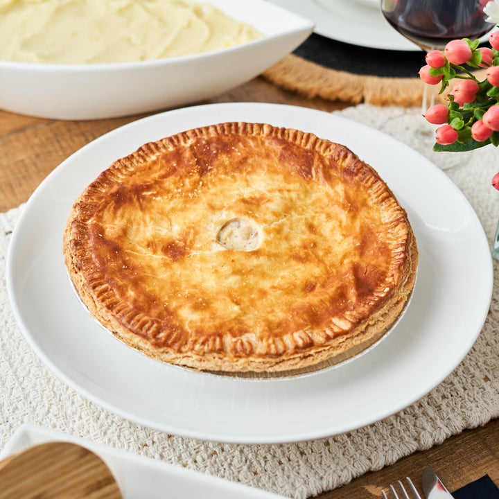roasted mushroom & white bean pie on a white plate with a side of mashed potatoes and a glass of red wine in the background.
