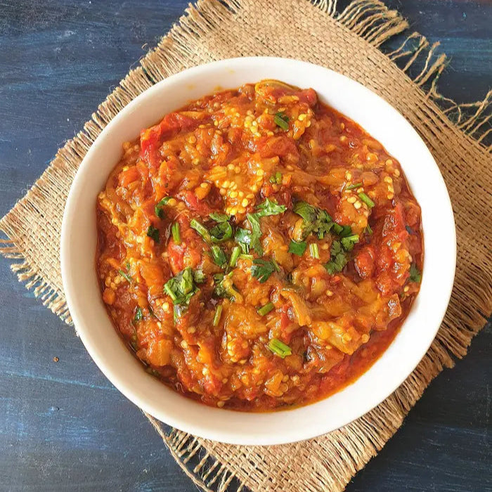 a smoky, spiced eggplant and tomato dish on a textured blue surface