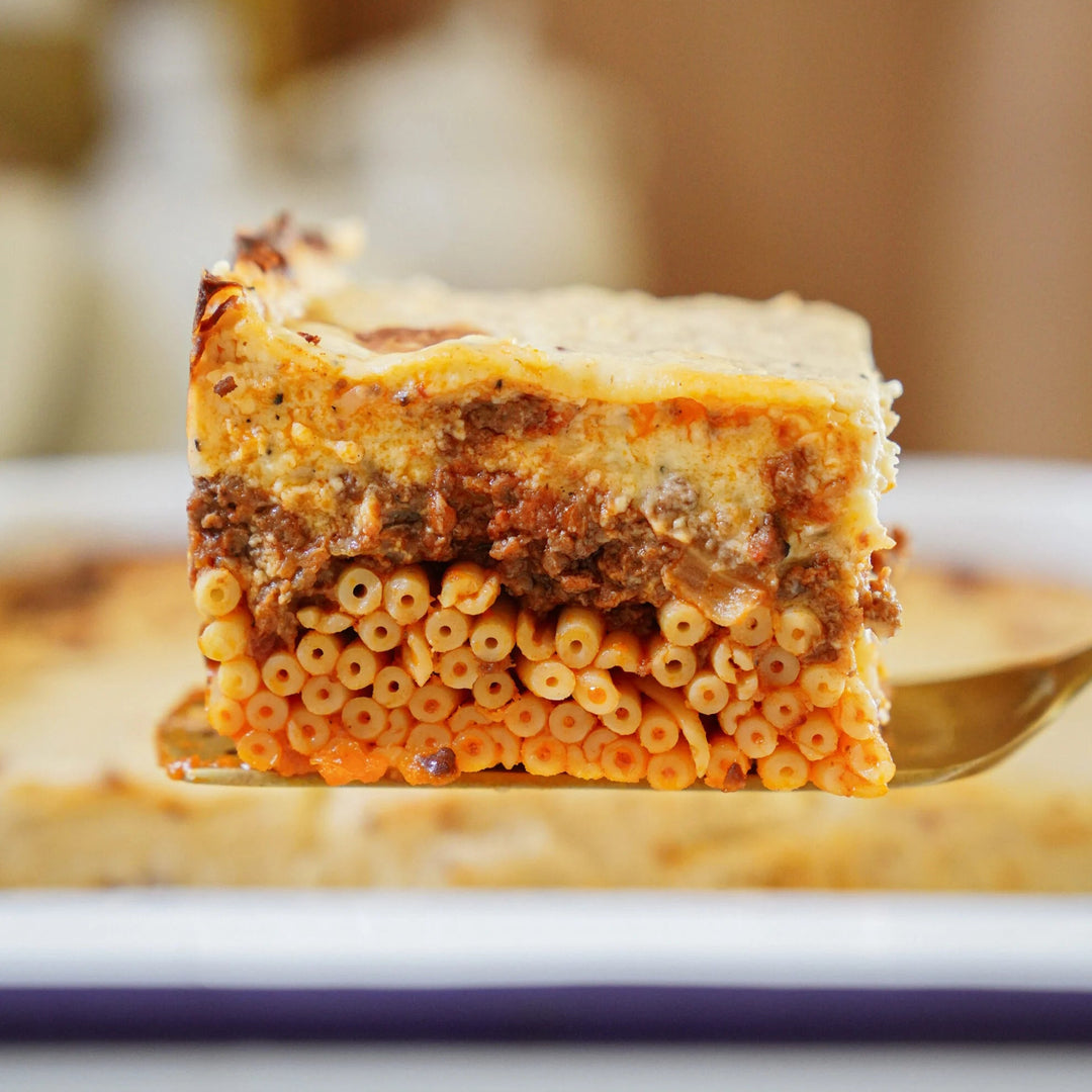 a layered pasta casserole with braised minced lamb, a touch of spice, and a luxuriously creamy béchamel topping