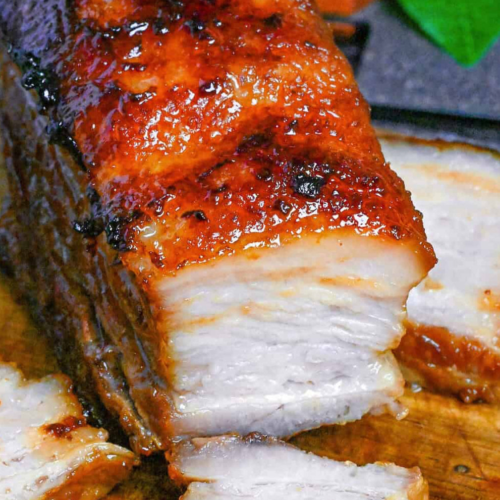 Sliced roasted pork belly on a wooden cutting board