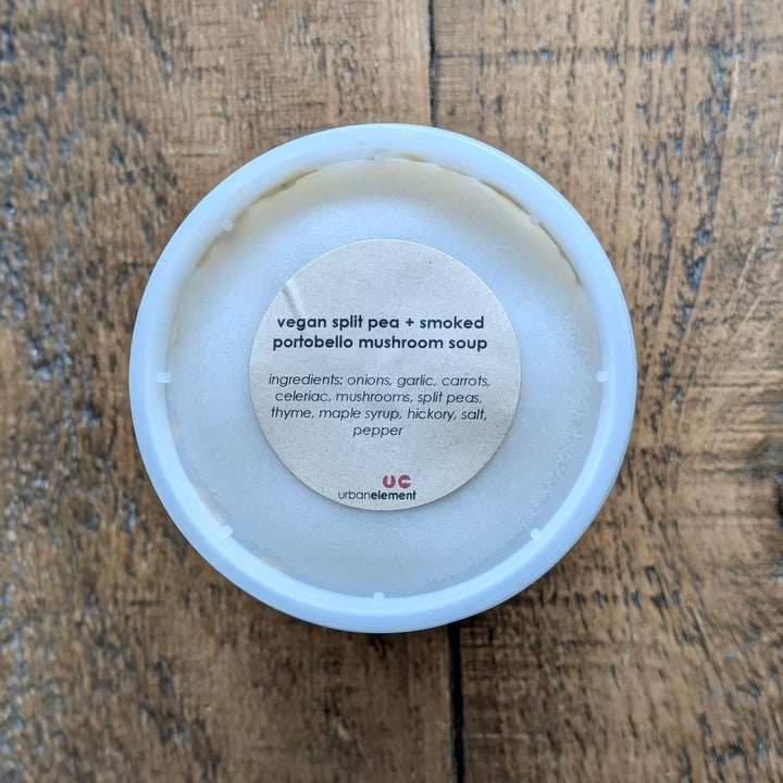Container of vegan split pea and smoked portobello mushroom soup on a wooden surface